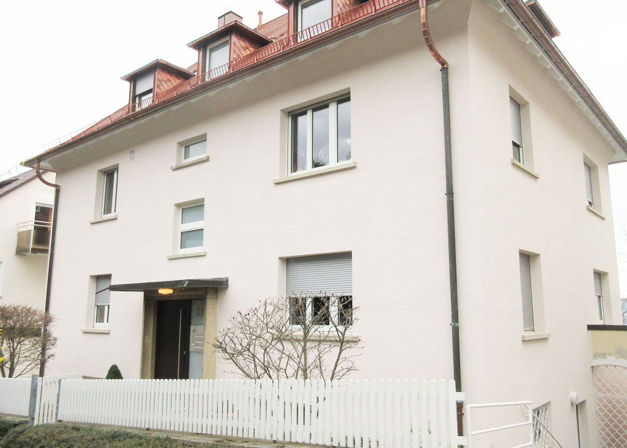 Ein Mehrfamilienhaus in Gauben Kupfer mit heller Fassade.