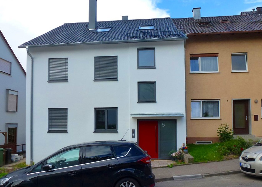 Vorderansicht eines Reihenendhaus mit roter Haustür.
