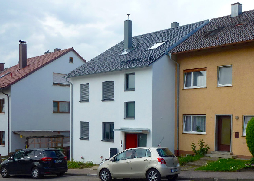Straßenansicht eines Reihenendhaus mit roter Haustür.