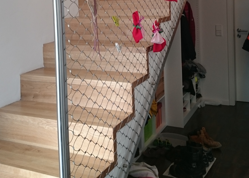 Treppe mit Holzstufen und Fangnetz.