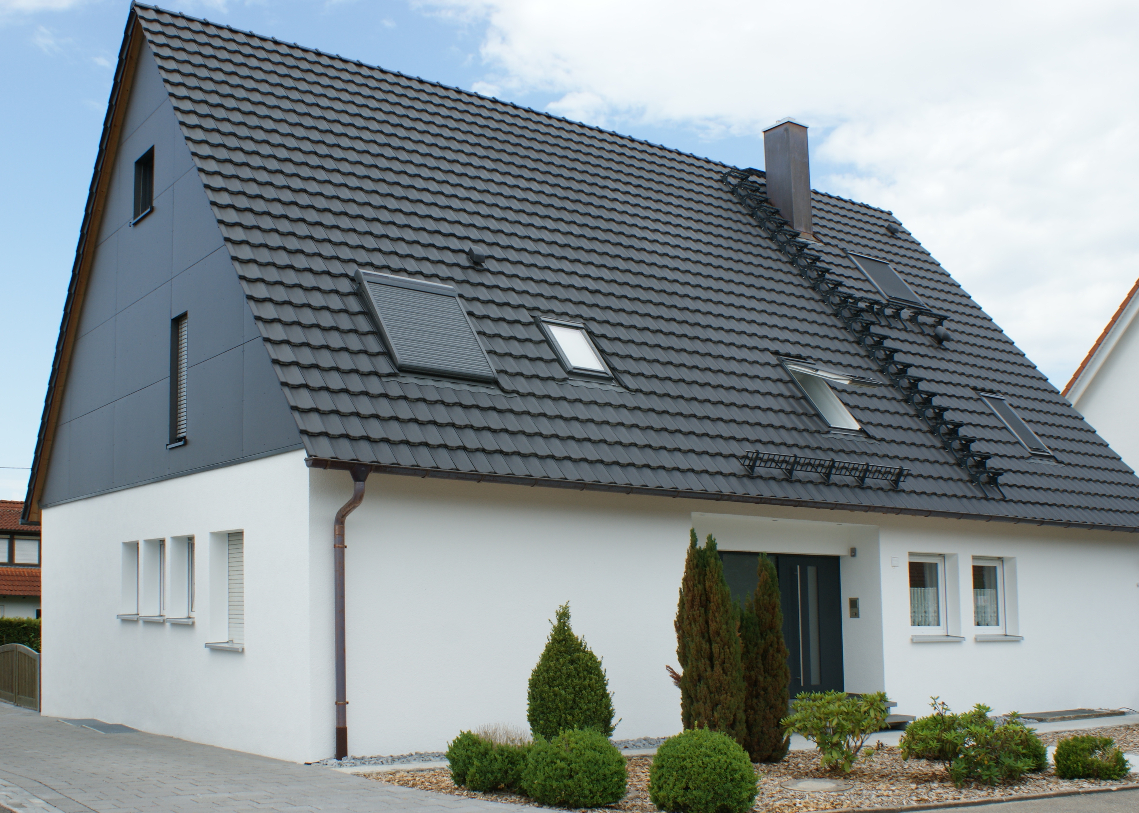 Seitenansicht eines Spitzdachhaus mit grauem Dach.